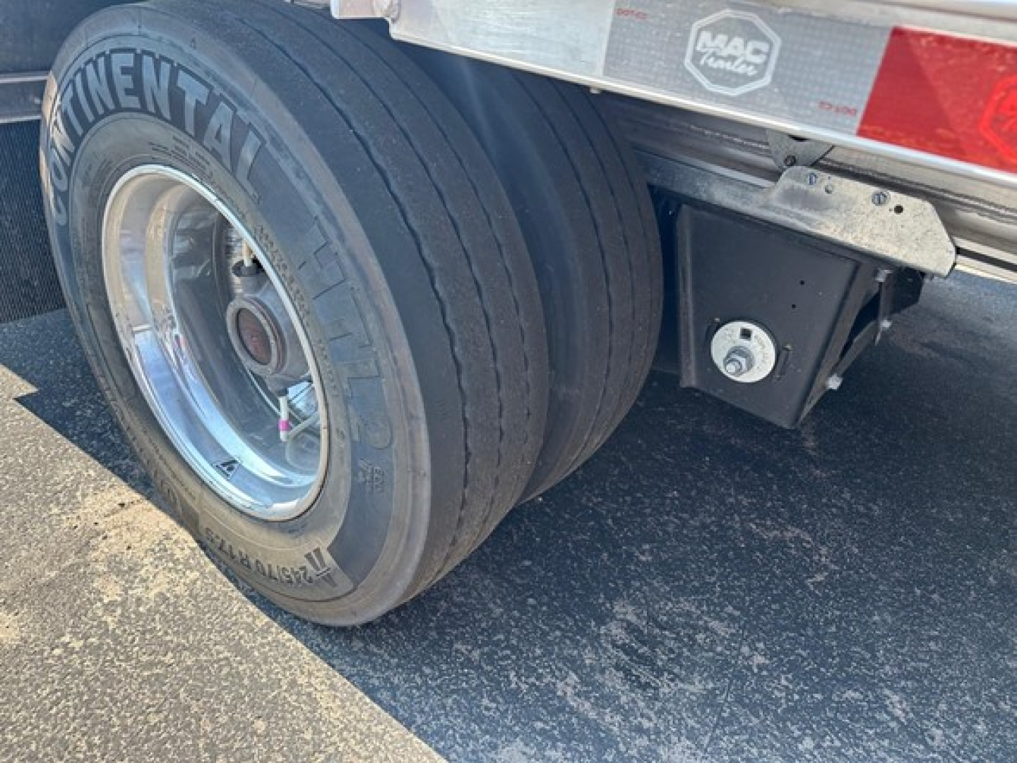 Trailer air-suspension dual rear axles with Continental tire, chrome wheel, MAC trailer logo plate, side-frame toolbox visible.