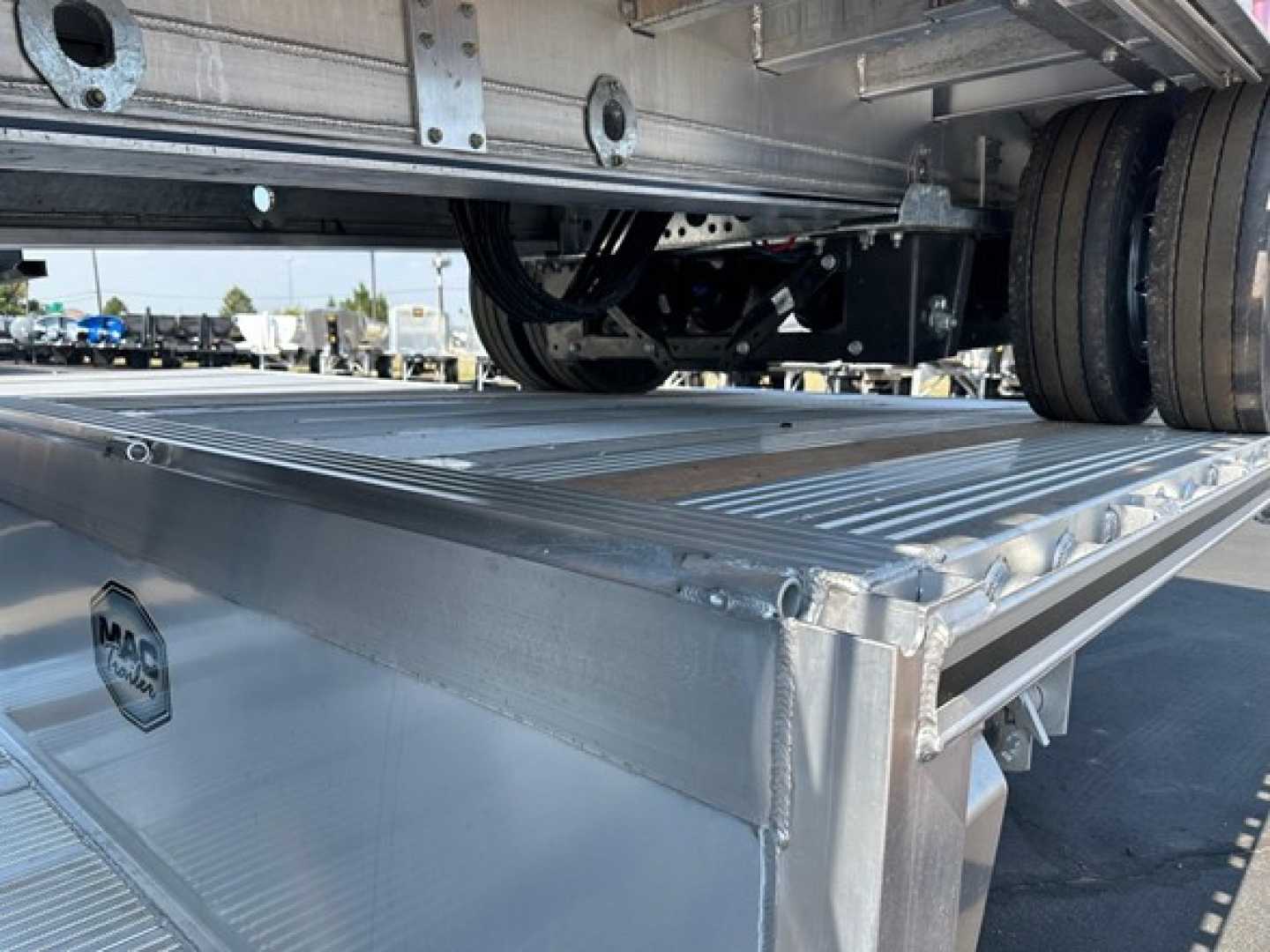 Mac trailer drop deck showing aluminum deck edge and wheel area with MAC badge visible