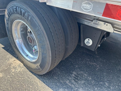 Trailer axle with dual tires and metal frame showing Continental tire brand and wheel well of Mac 53' drop deck trailer.