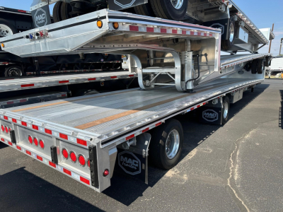 Aluminum drop deck trailer showing multiple deployed loading ramps and rear lighting, MAC trailer branding, and a spare tire on the side.