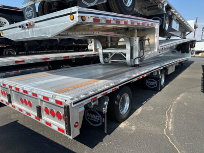 Trailer in-bed view of Mac drop deck trailer showing aluminum flatbed with side rails and rear lighting.