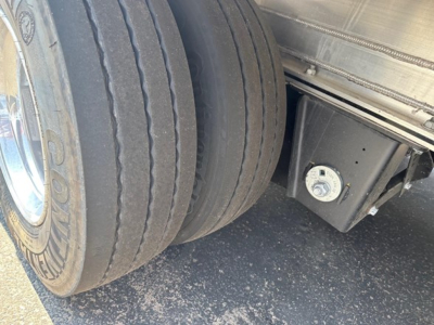 Trailer wheelset and undercarriage with dual tires and a securing mechanism visible under a Mac drop deck trailer.