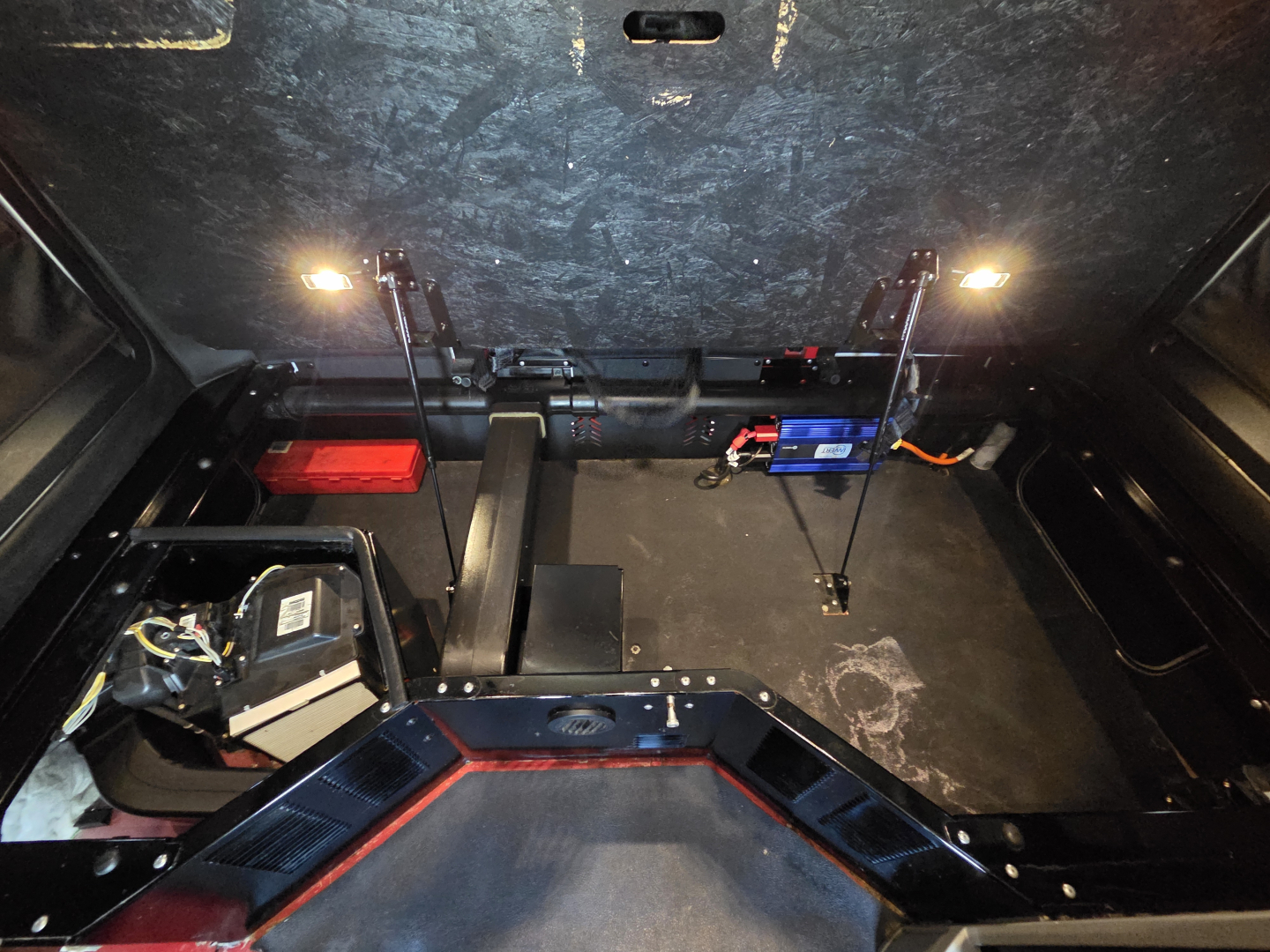 Kenworth T680 cab interior with storage and battery, showing two small lights and wiring harnesses.