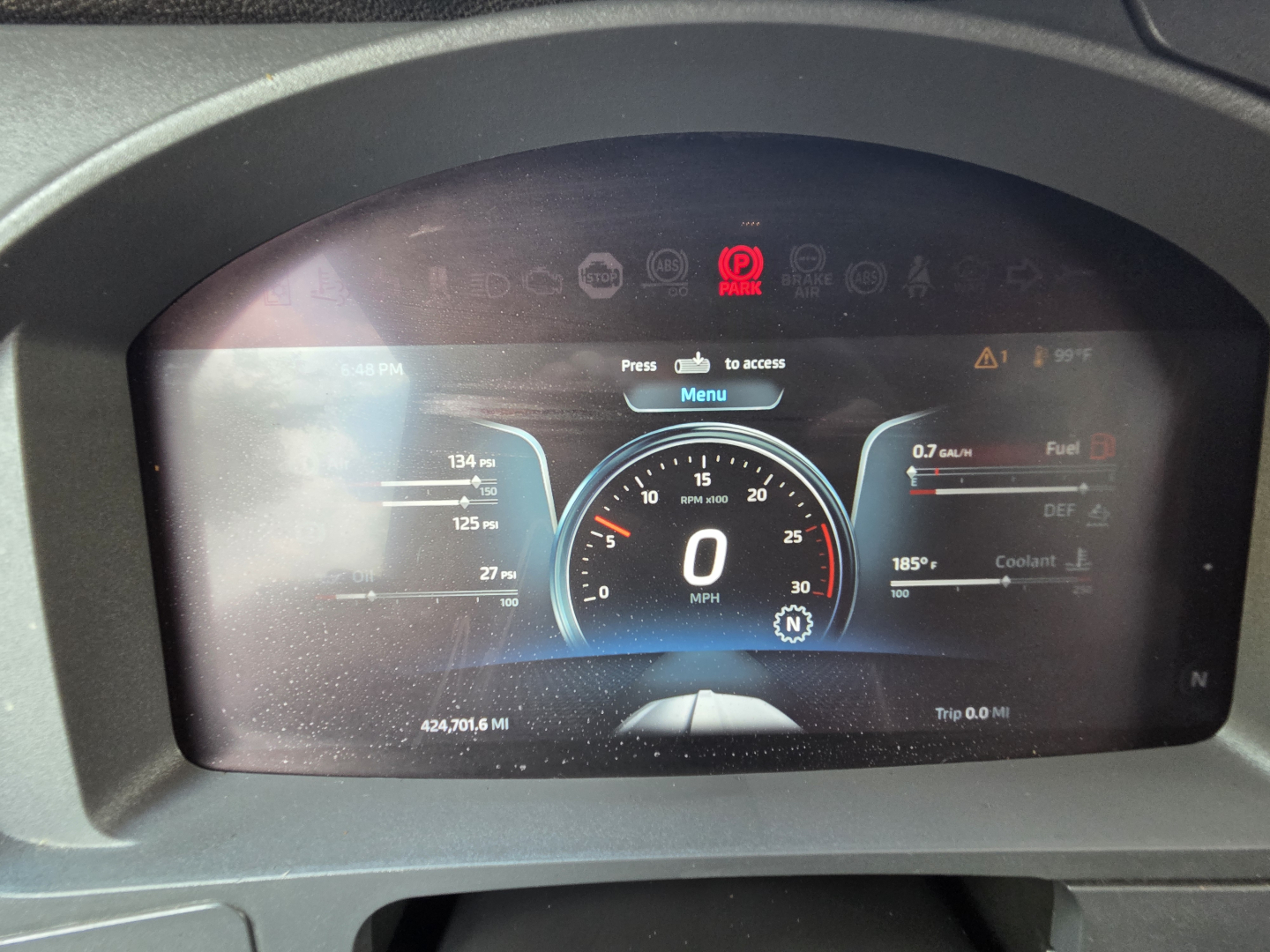 Digital instrument cluster showing speedometer 0 mph, fuel, DEF, coolant gauges and warning icons in Kenworth T680 cab; odometer 424,701.6 mi.