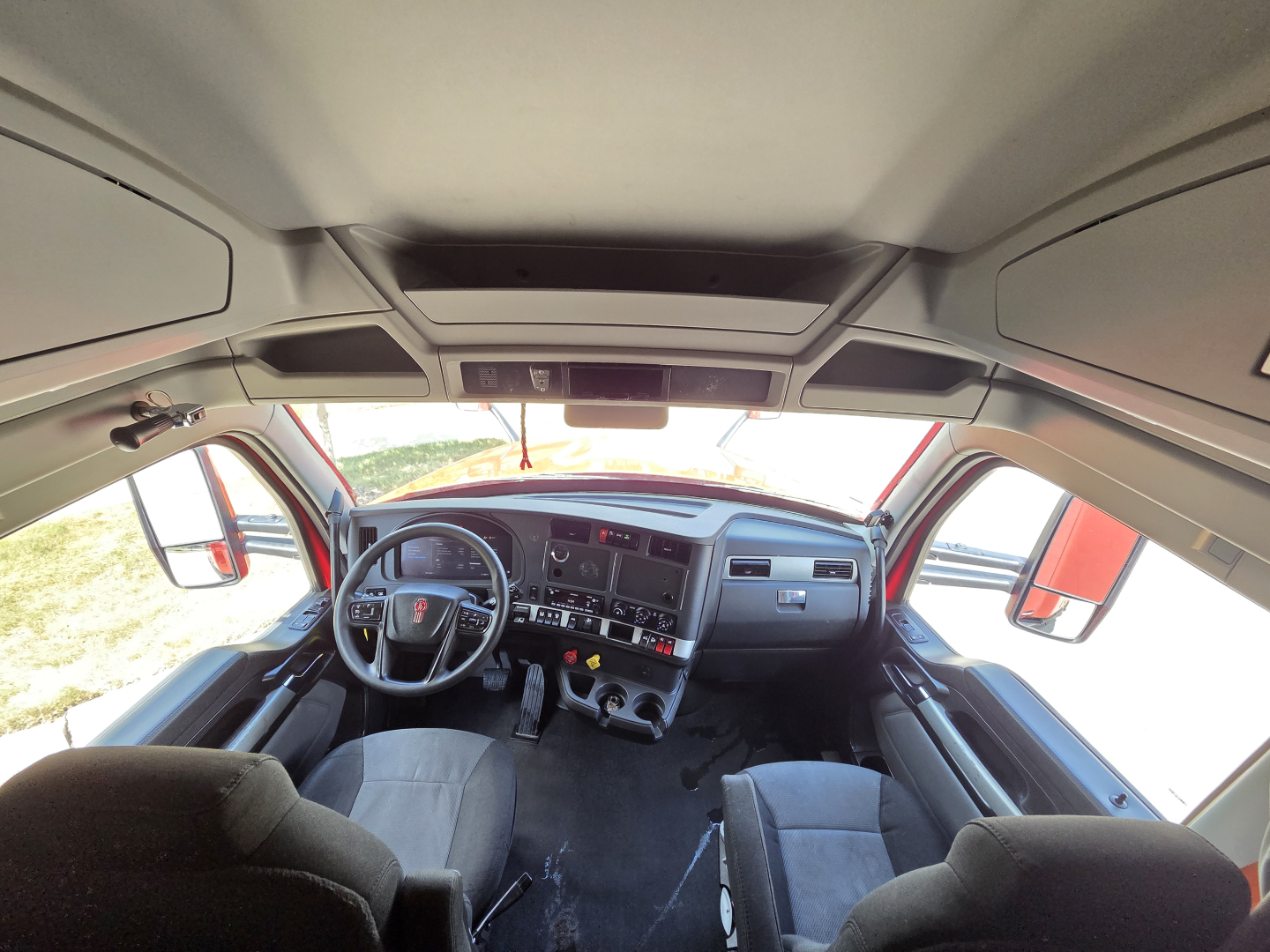 Kenworth T680 interior cab showing dashboard and steering wheel, front windshield, driver and passenger seats.