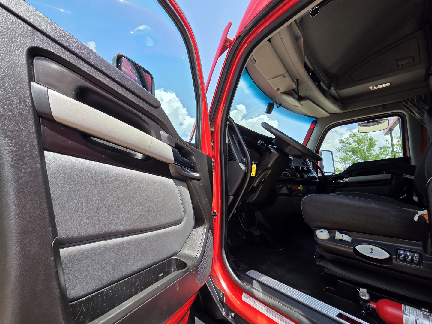 Kenworth T680 truck interior and open driver door showing cabin seating and dashboard details.