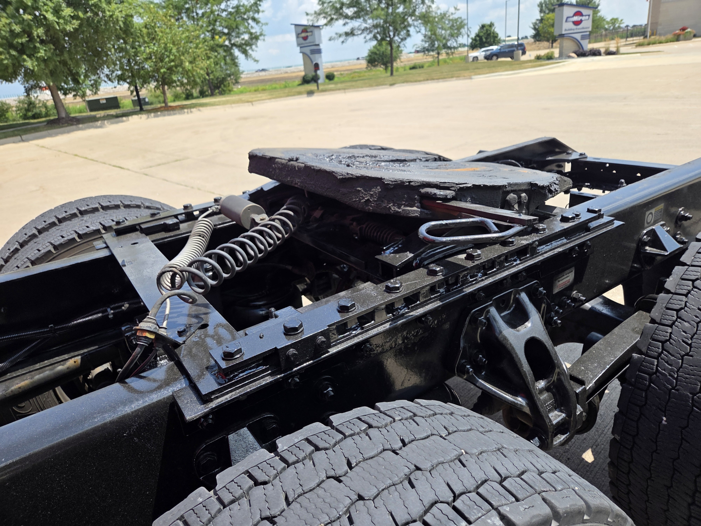 Kenworth T680 truck chassis showing fifth wheel mounting and suspension components, dual rear axles, exposed wiring, and hitch area.