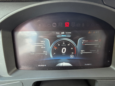 Digital instrument cluster showing speedometer 0 mph, fuel, DEF, coolant gauges and warning icons in Kenworth T680 cab; odometer 424,701.6 mi.