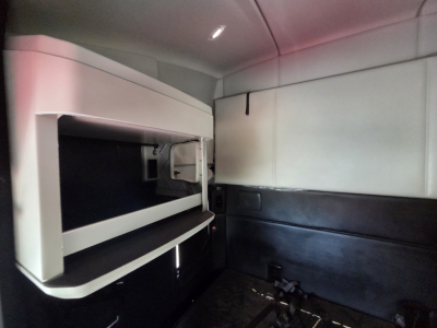 Interior of Kenworth T680 sleeper cab showing bunk area with storage shelf and dark seating area