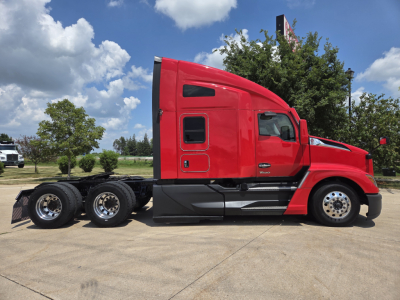 Kenworth T680 tractor in red, side view showing cab with sleeper and dual rear axles on trailerless chassis.