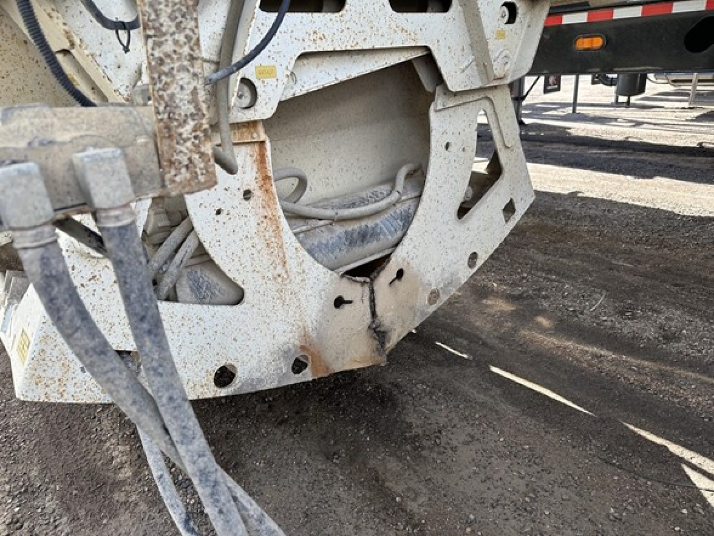 Dump trailer undercarriage showing steel frame with rust spots and U-shaped crossmember near wheel well.