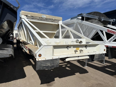 Dump trailer showing rear and side view with steel bottom and triangular frame, white paint, taillights, and bumper.