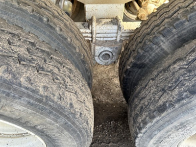 Dump trailer axle close-up showing dual wide tires and suspension hanger.