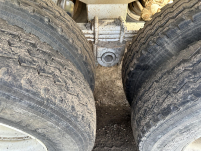 Dump trailer hitch area showing dual rear tandem wheels with tire treads and central hitch mount.