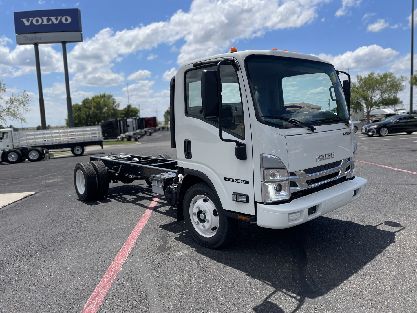 Isuzu NRR-GAS cab and chassis truck front-right view showing white cab, chassis frame, and Isuzu emblem.