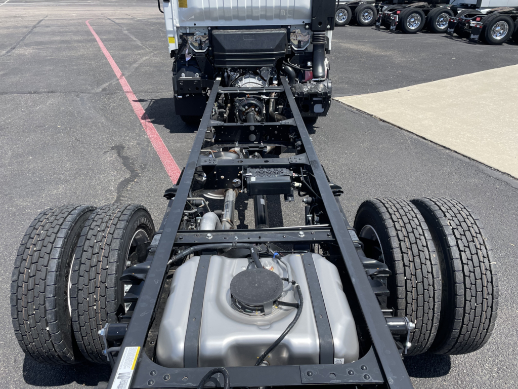 Isuzu NRR cab and chassis frame showing fuel tank and dual rear axles with chassis rails and cab in background.