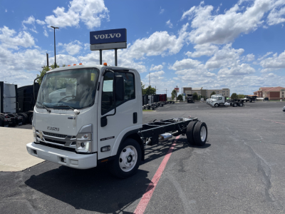 Isuzu NRR cab and chassis truck in a dealership lot showing front view with chassis back, Isuzu logo, and Volvo sign in background.