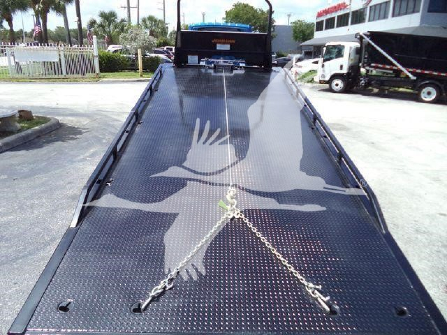 Trailer bed of 2027 International MV rollback truck showing diamond plate surface and safety chains across bed.