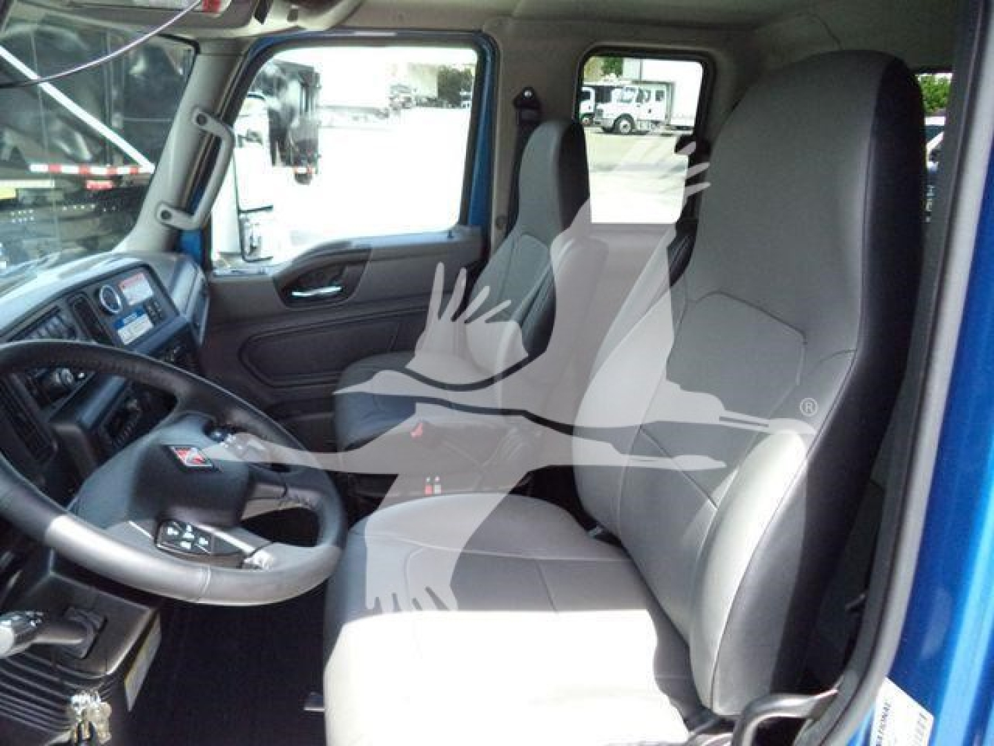 Truck cab interior showing driver and passenger seats with steering wheel and dashboard in a blue International MV cab.