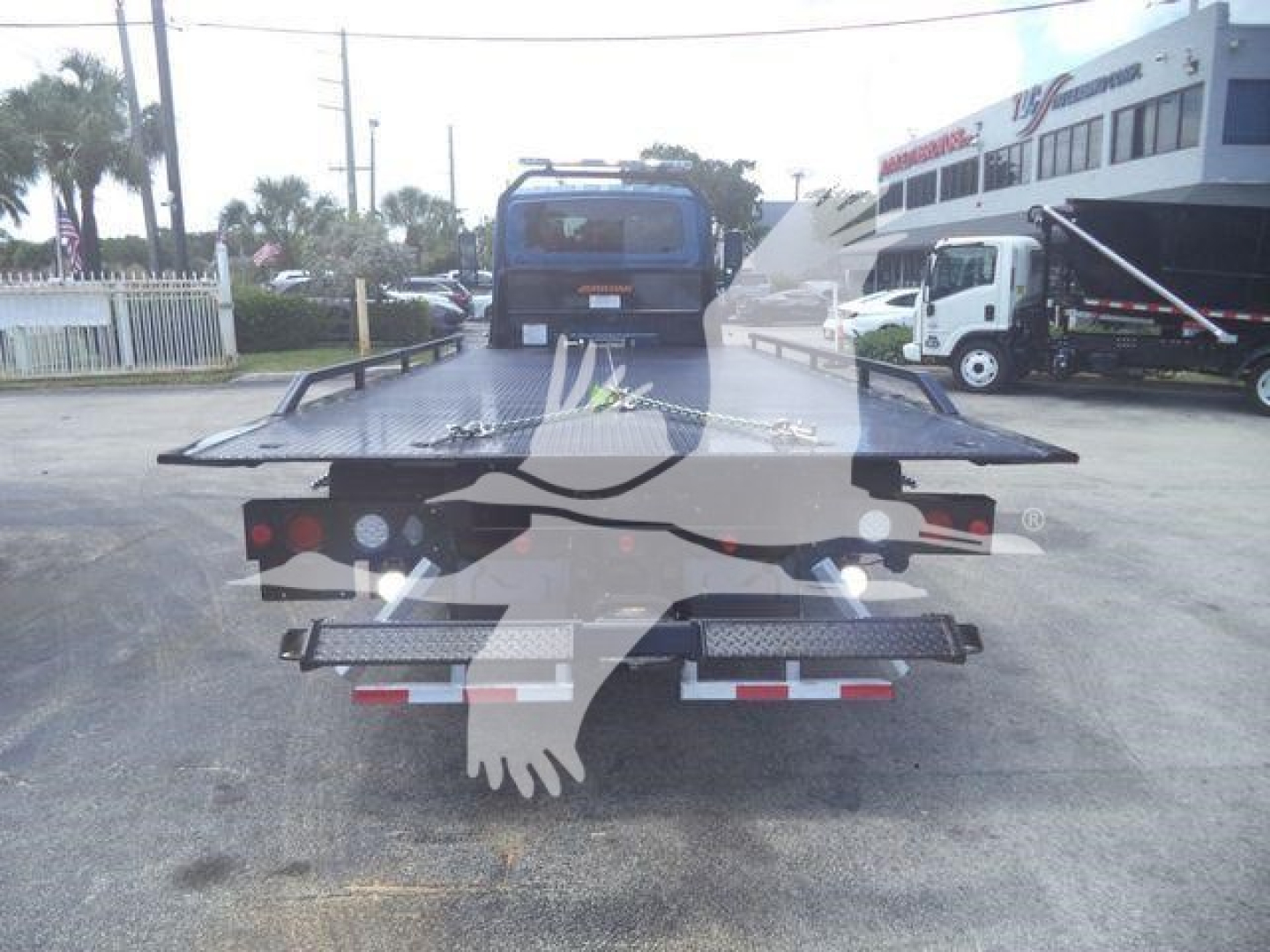 Flatbed tow truck bed with rear platform and lights, viewed from the back.