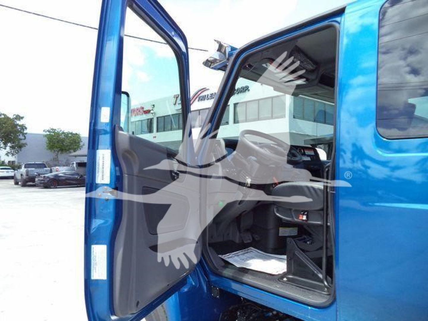 Truck cab interior and open driver-side door of a blue 2027 International MV rollback truck showing the dashboard and seating area.