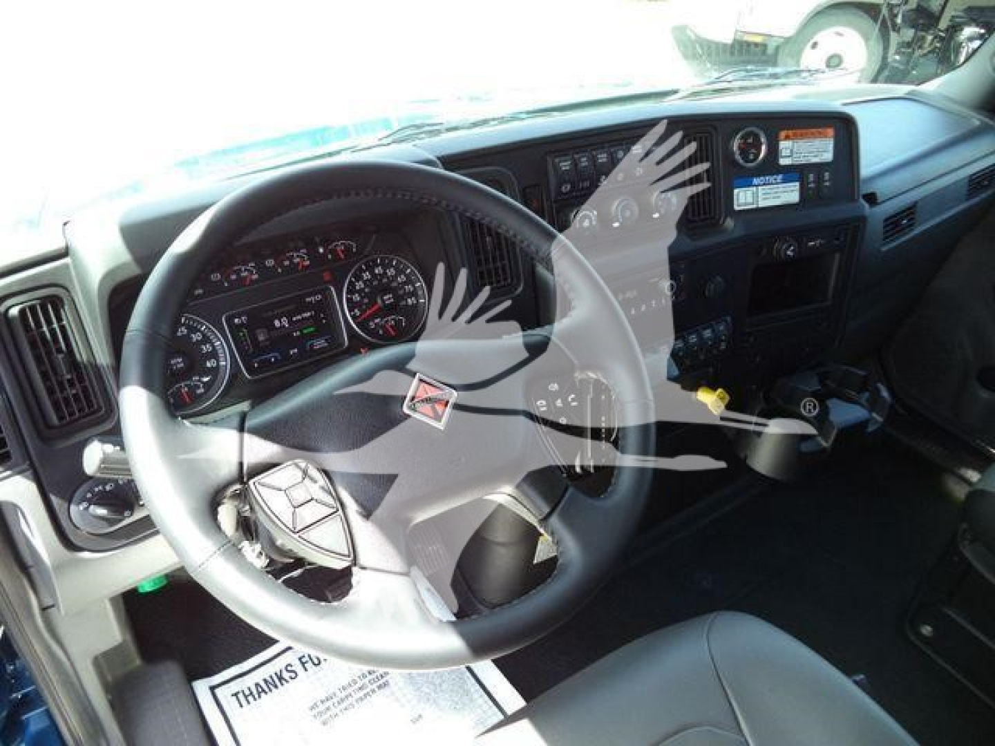 Truck interior showing steering wheel and dashboard of a 2027 International MV, with instruments and control panel visible.