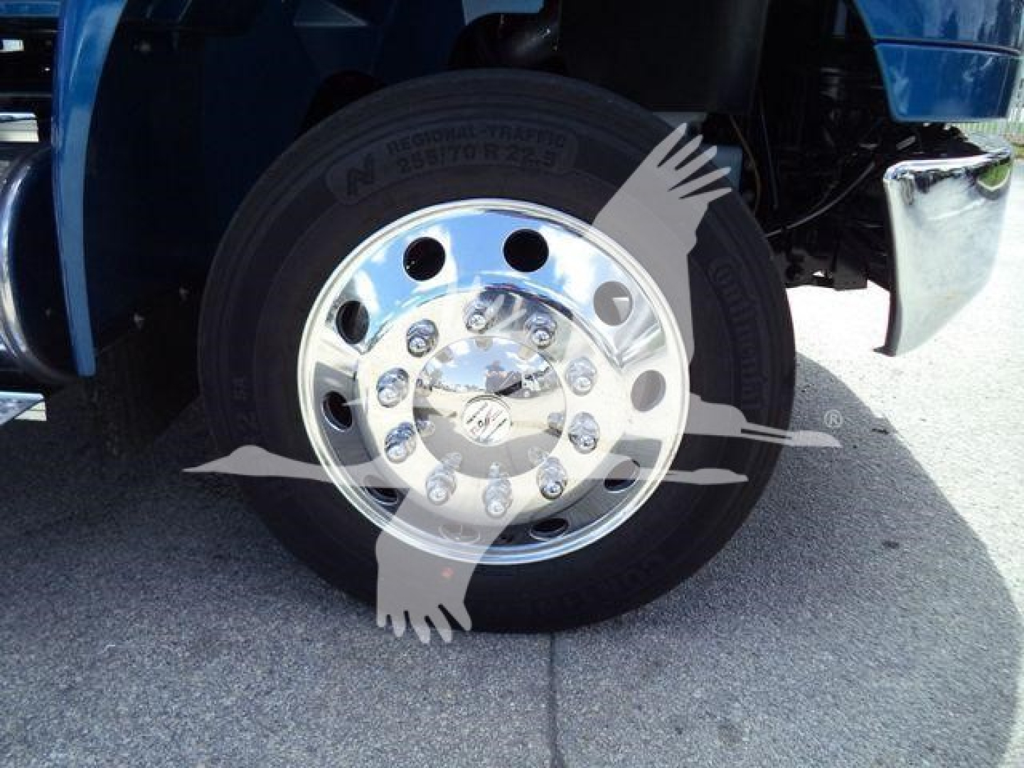 Wheel and chrome hubcap of a blue International MV truck front wheel with tire and fender visible.