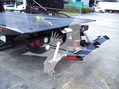 Truck rollback equipment on rear of 2027 International MV; diamond plate platform with hydraulic ramps and taillights visible.