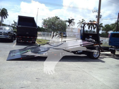 Tow truck flatbed rollback in a lot showing a black truck with a low-profile flatbed and dual rear wheels.
