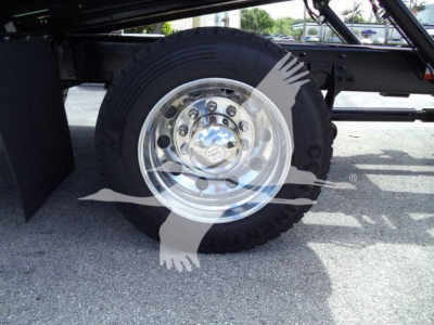 Truck wheel and undercarriage view showing a polished chrome wheel with black tire; overlay watermark with a faint hand and ribbon across the image.