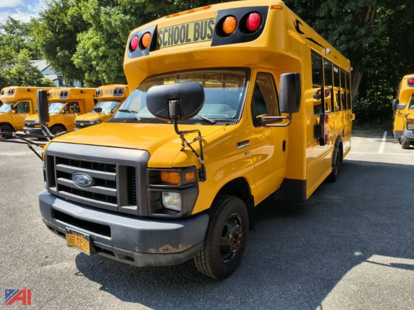 Ford E-Series school bus front-left view, yellow body, black grille, large side mirrors, SCHOOL BUS sign above windshield.