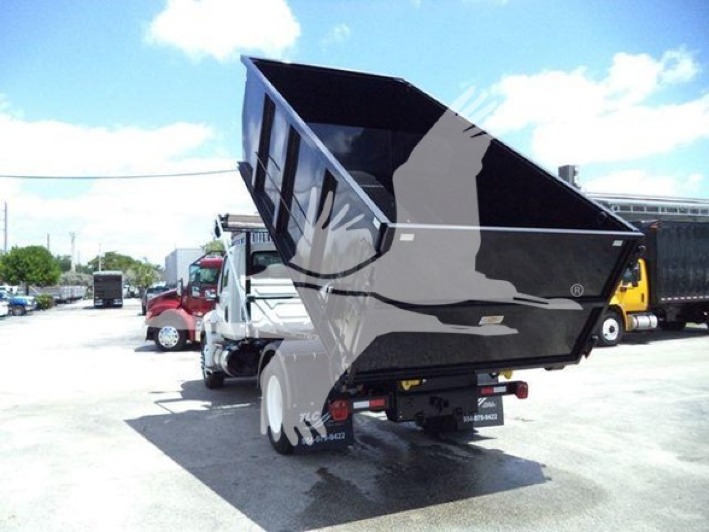Truck chassis showing dump bed raised on a 2019 International Durastar 4300 roll-off. Visible text on the rear shows stock number and dealer markings.