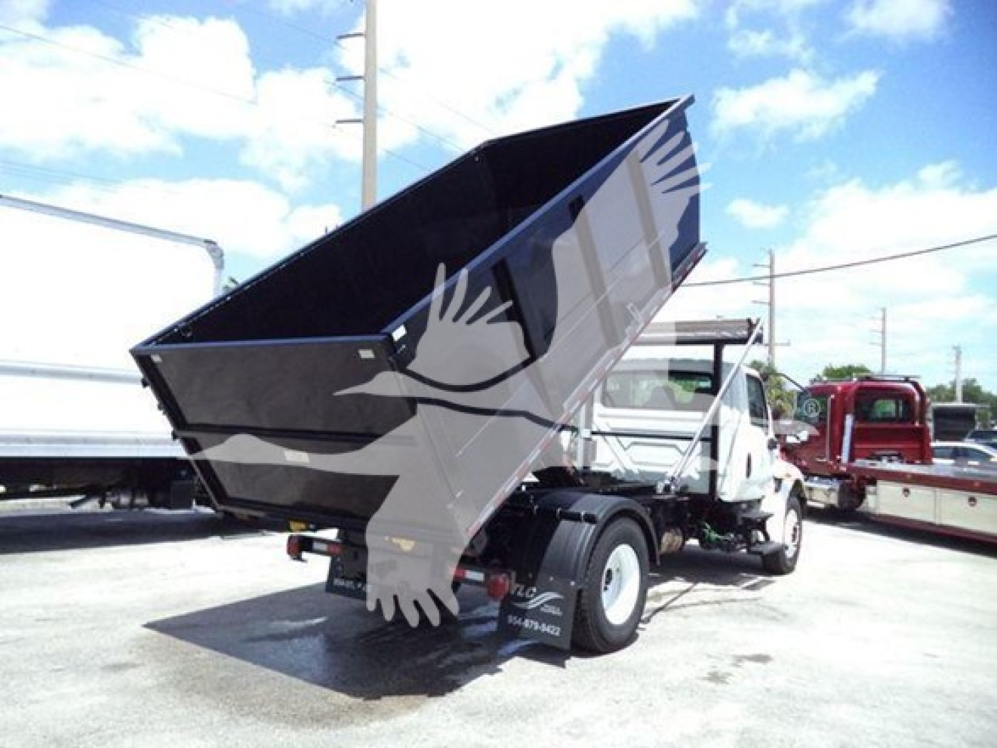 Dump truck bed raised showing hydraulic system and International Durastar 4300 cab in a used roll-off truck configuration.