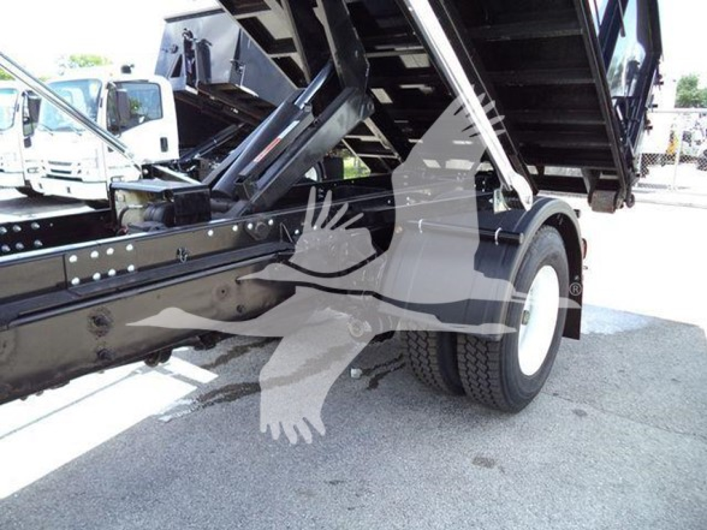 Truck bed area of a 2019 International Durastar 4300 roll-off showing hydraulic bed and rear wheel.