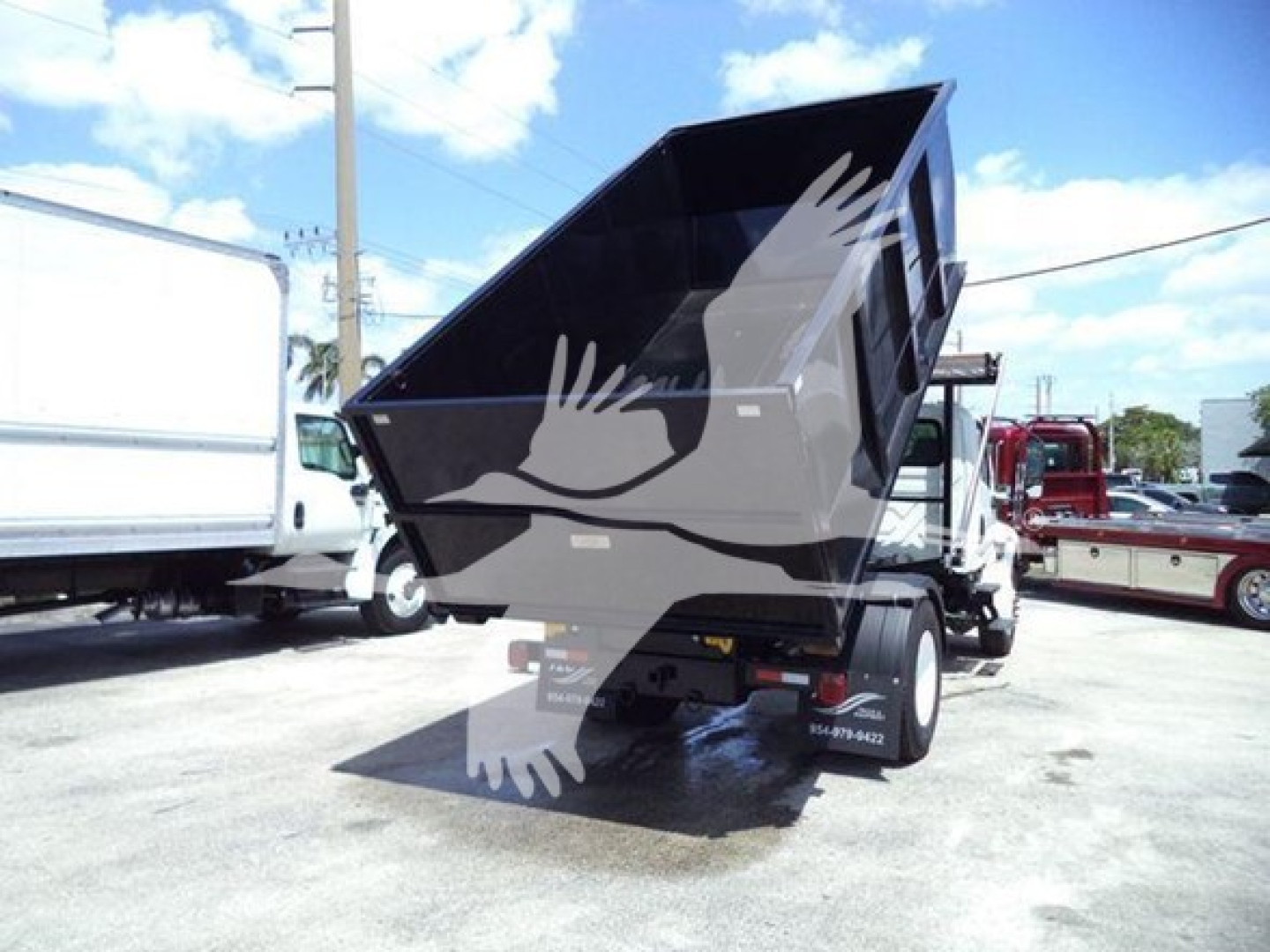 Dump truck bed raised showing rear view with hydraulic arms and dual rear wheels on a 2019 International Durastar 4300 roll-off truck.