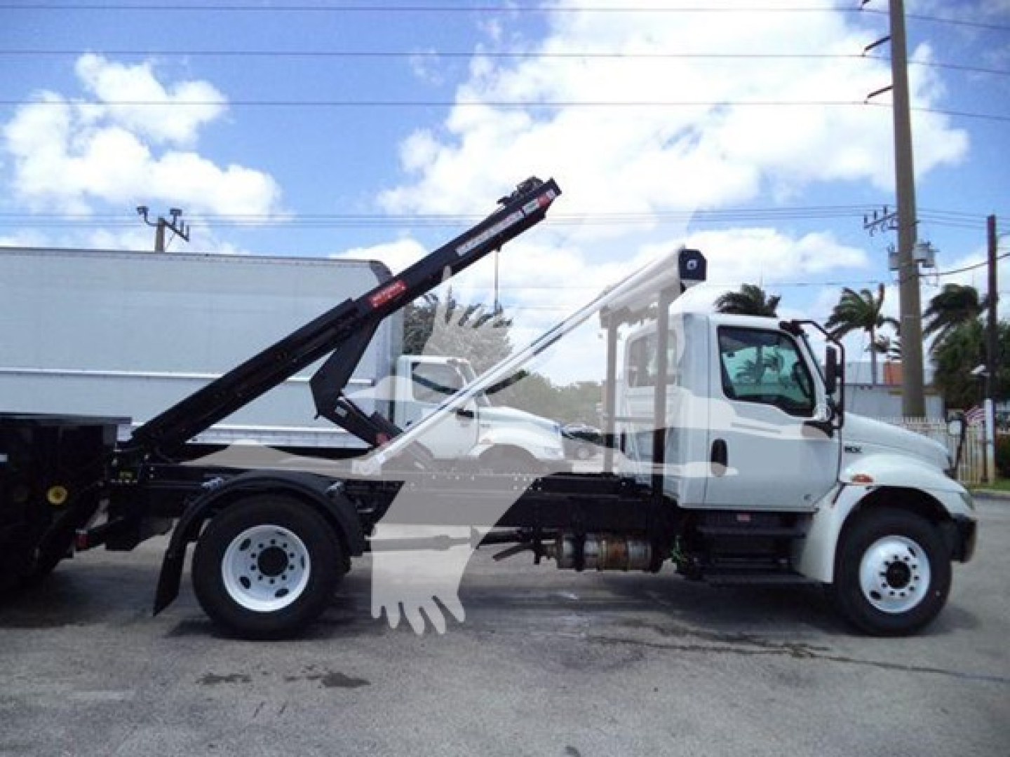 Isuzu International Durastar 4300 roll-off truck side view with hydraulic lift arm in white cab and black chassis.