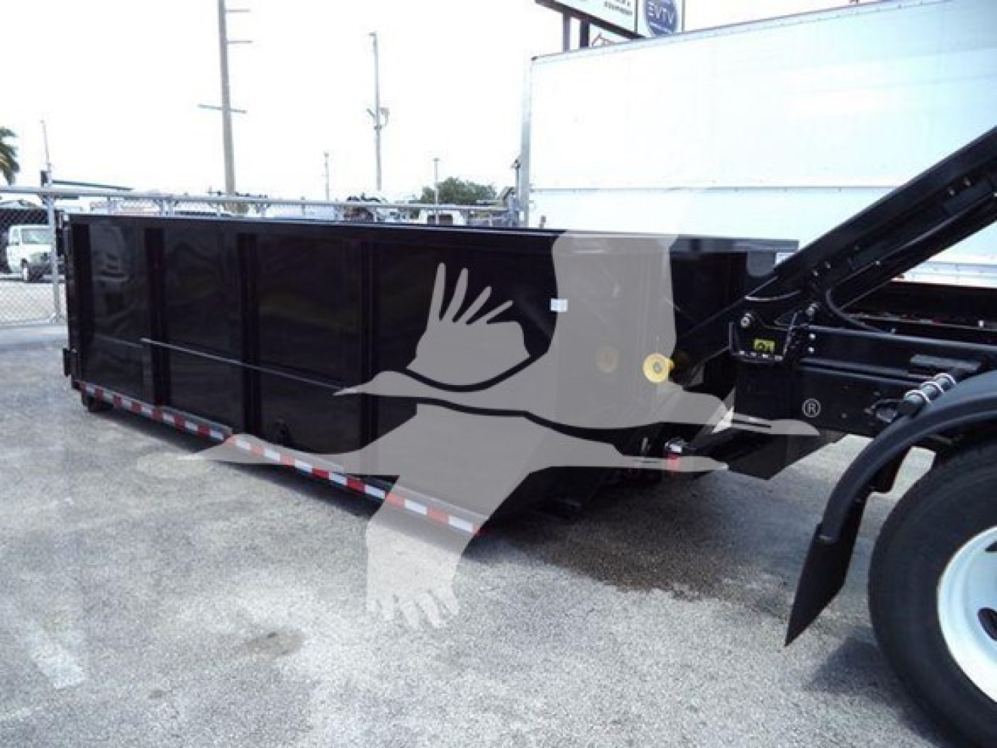 Rol-off truck bed on a 2019 International Durastar 4300 showing a black steel dump-style cargo bed with hydraulic mechanism and front wheel, VIN label not visible.