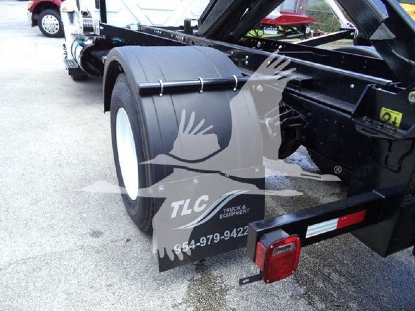 Truck chassis side view showing rear dual wheels and frame with fender and taillight assembly; TLC truck equipment watermark overlay