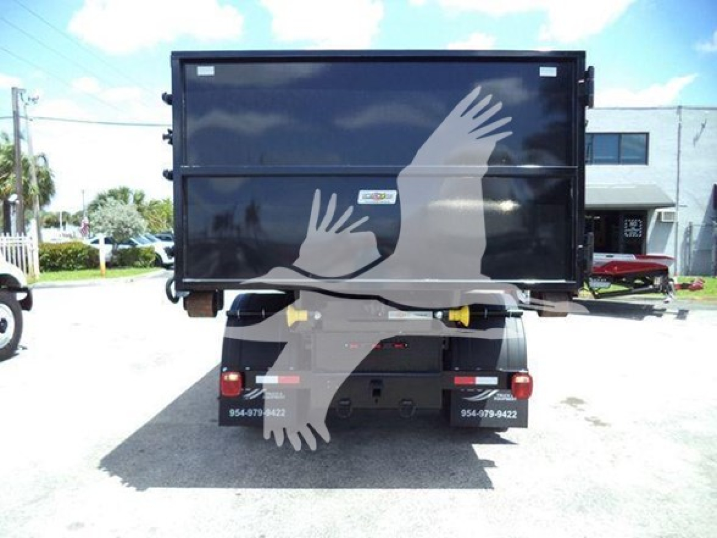 Dump bed truck shown from rear with large black dump body and dual rear lights.
