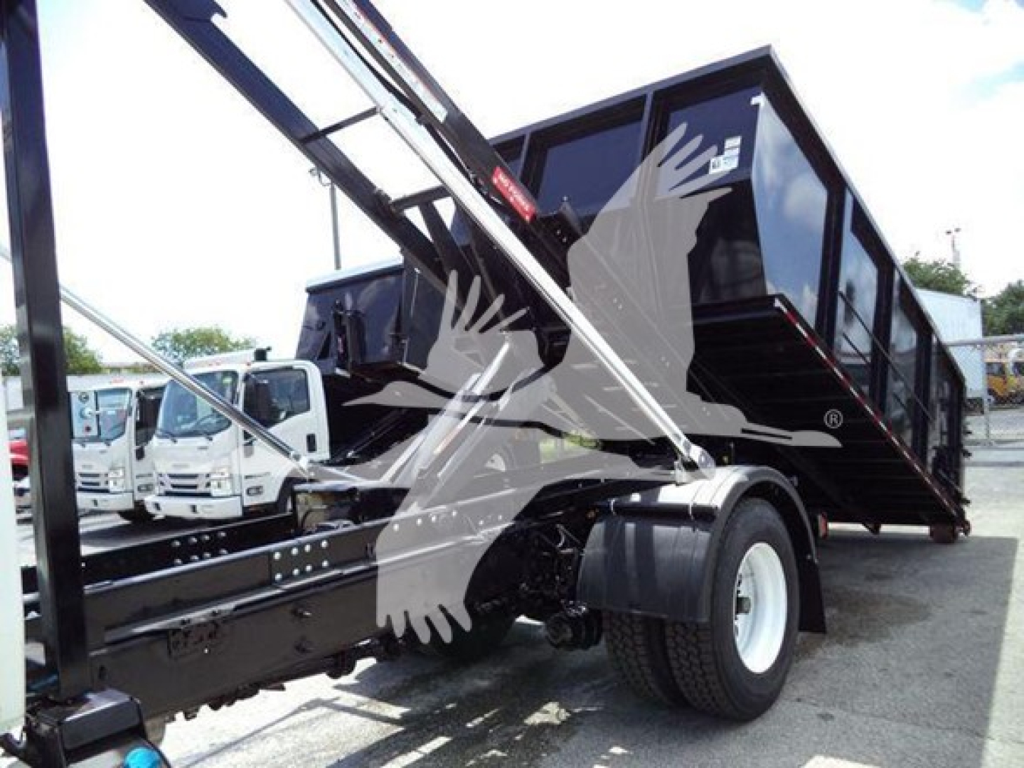 Truck bed and hooklift system of a 2019 International Durastar 4300 rollover truck, side view showing the hydraulic lift and cargo bed structure.