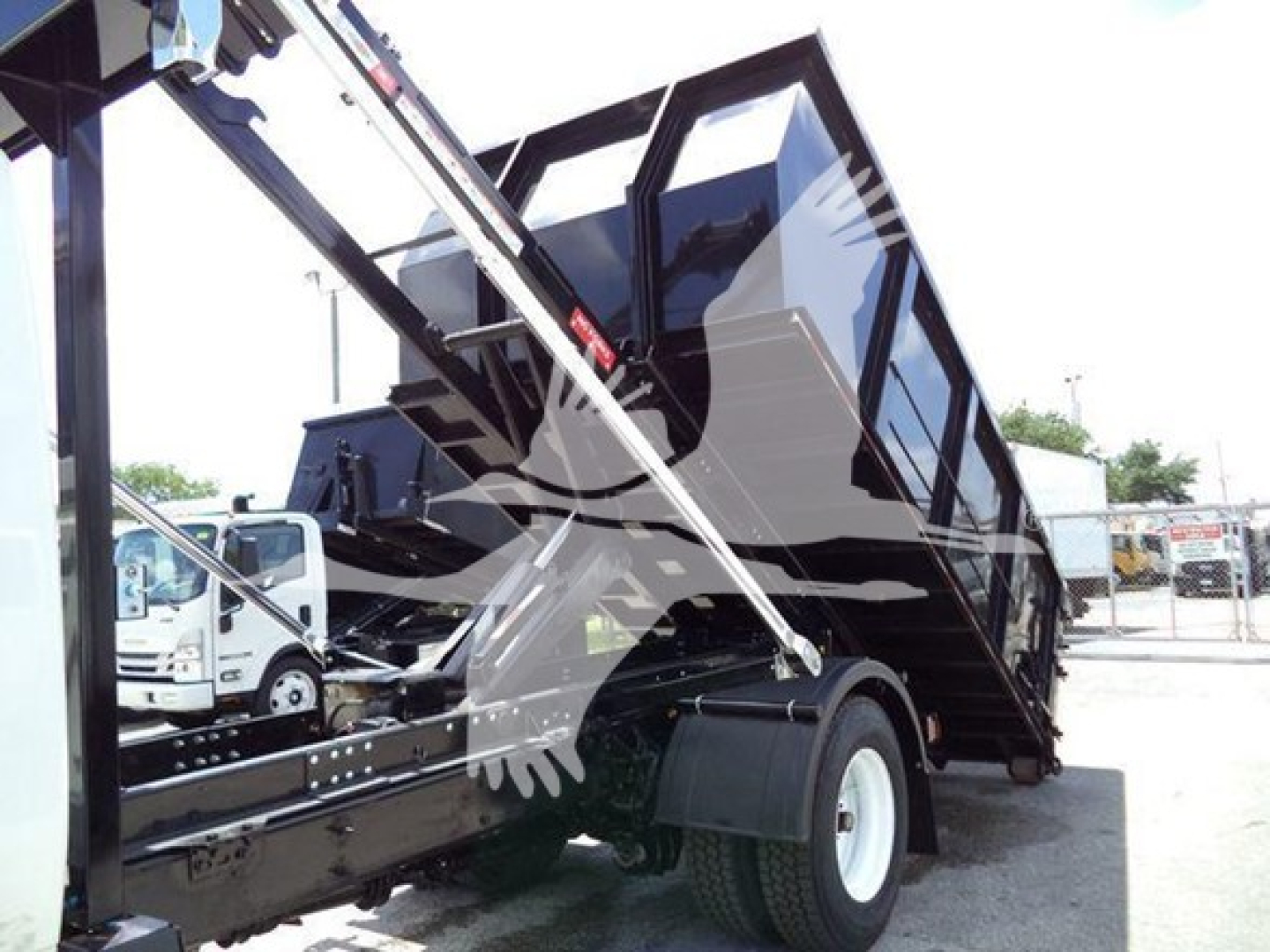 Truck dump body with hydraulic lift showing rollover container and cab side view.