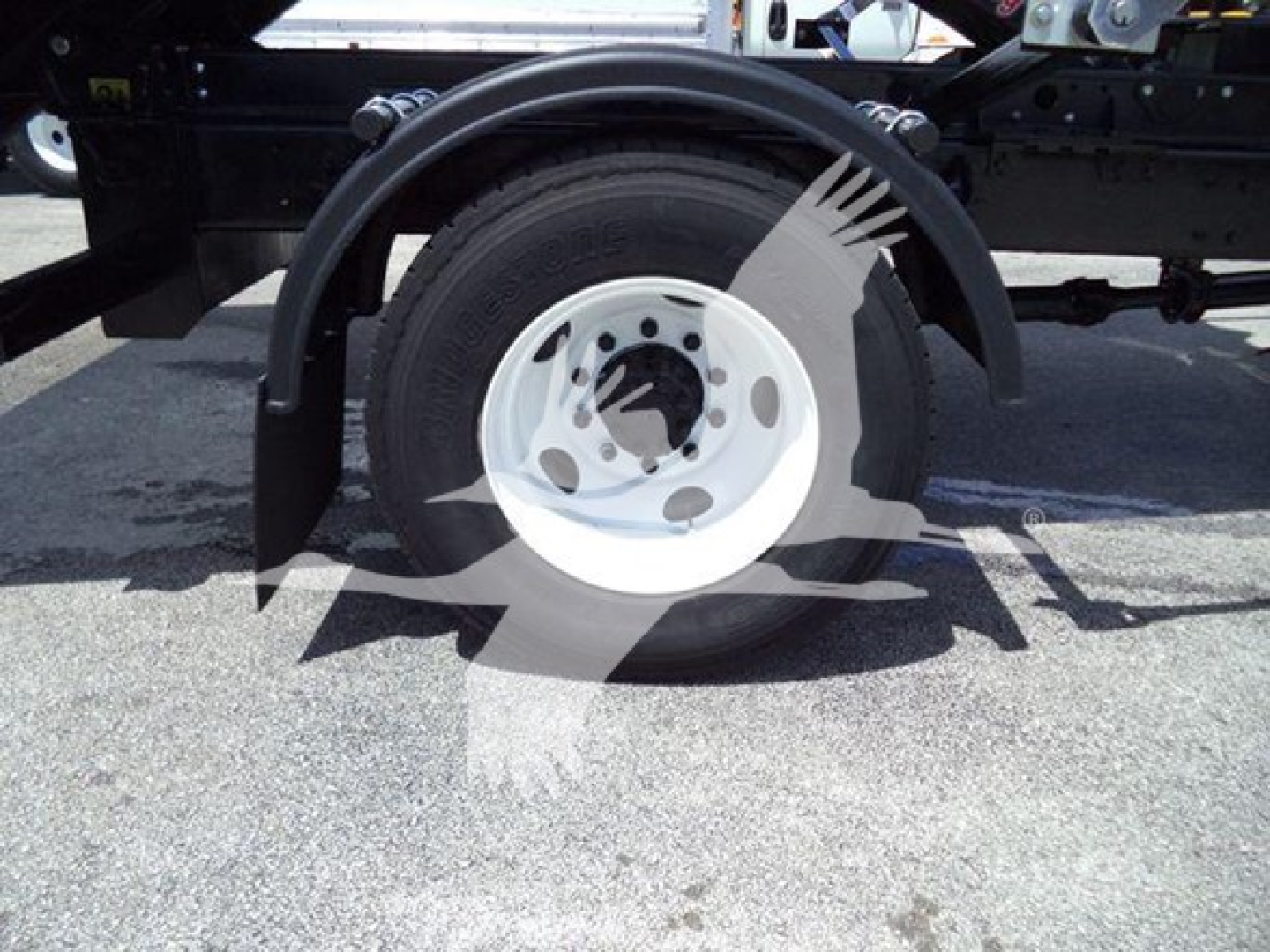 Wheel assembly and fender of a 2019 International Durastar 4300 roll-off truck showing a white steel rim and black fender.