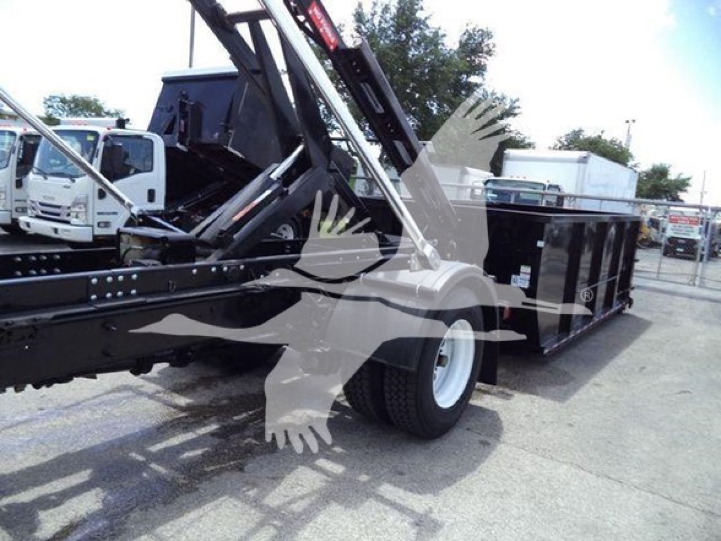 Truck chassis with crane/arm in a roll-off bed setup; no legible text visible on components in this image.
