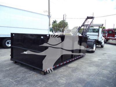 Black roll-off dumpster attached to a white International Durastar 4300 truck in a parking lot.