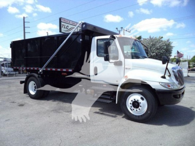 Truck bay showing 2019 International Durastar 4300 roll-off truck with black dump body and white cab.