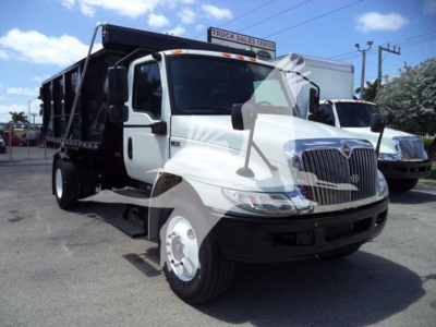Trucks showing a white 2019 International Durastar 4300 roll-off utility with a black dump bed in a dealership lot.