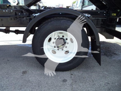Truck wheel and fender area showing a white steel rim and black tire under a roll-off dump bed chassis.