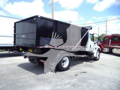 Truck bed with roll-off container mounted on International Durastar chassis. Side and rear view showing black container, white cab, and rear bumper.