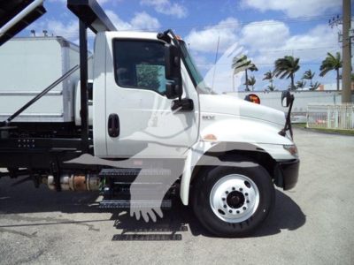 Truck cab side view of a 2019 International Durastar 4300 roll-off truck showing white cab, front wheel, side mirror, and ladder steps.