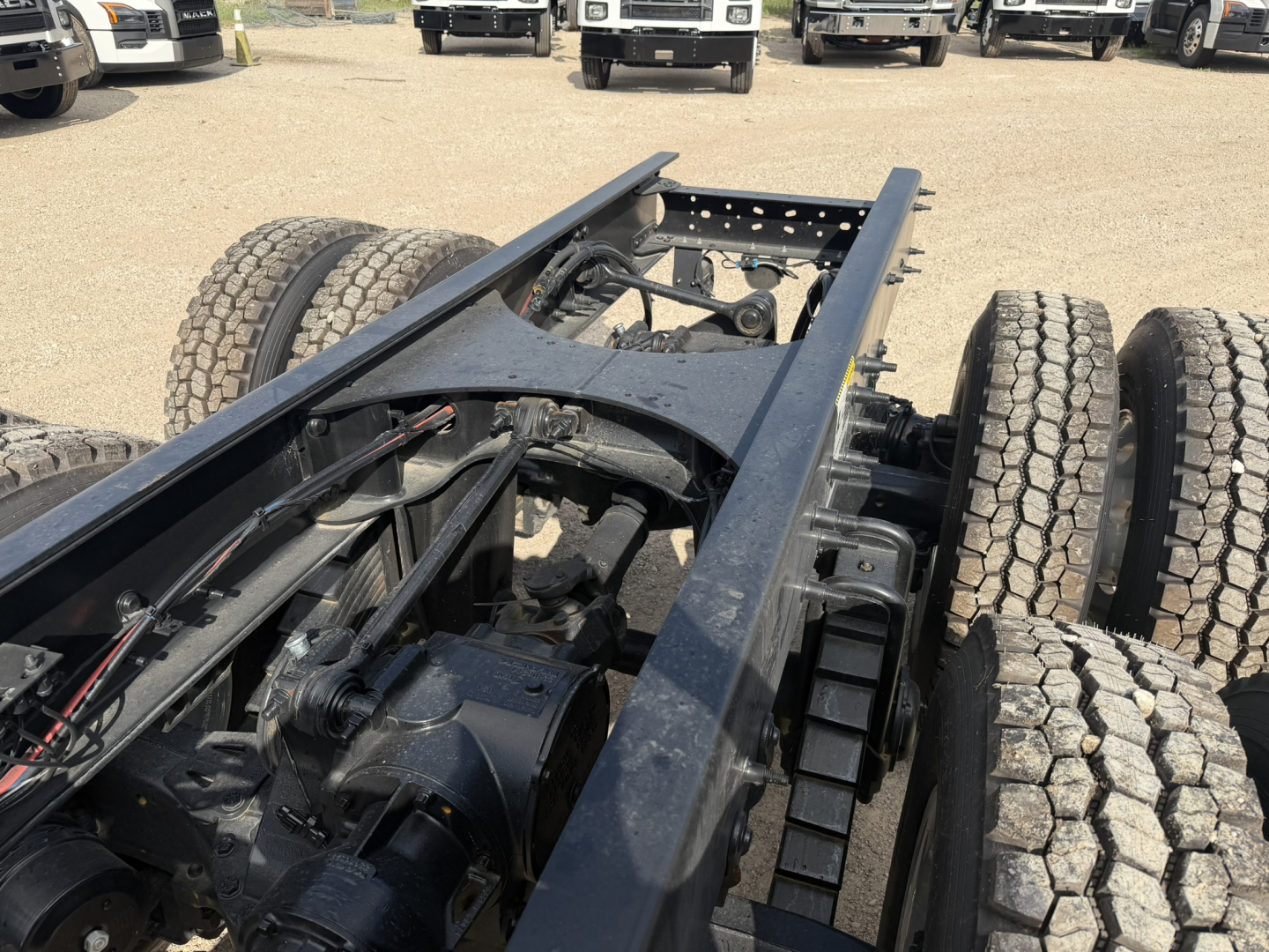Chassis frame of a 2026 Mack GR64F shown from rear-left side with dual rear axles and cabless chassis components visible.